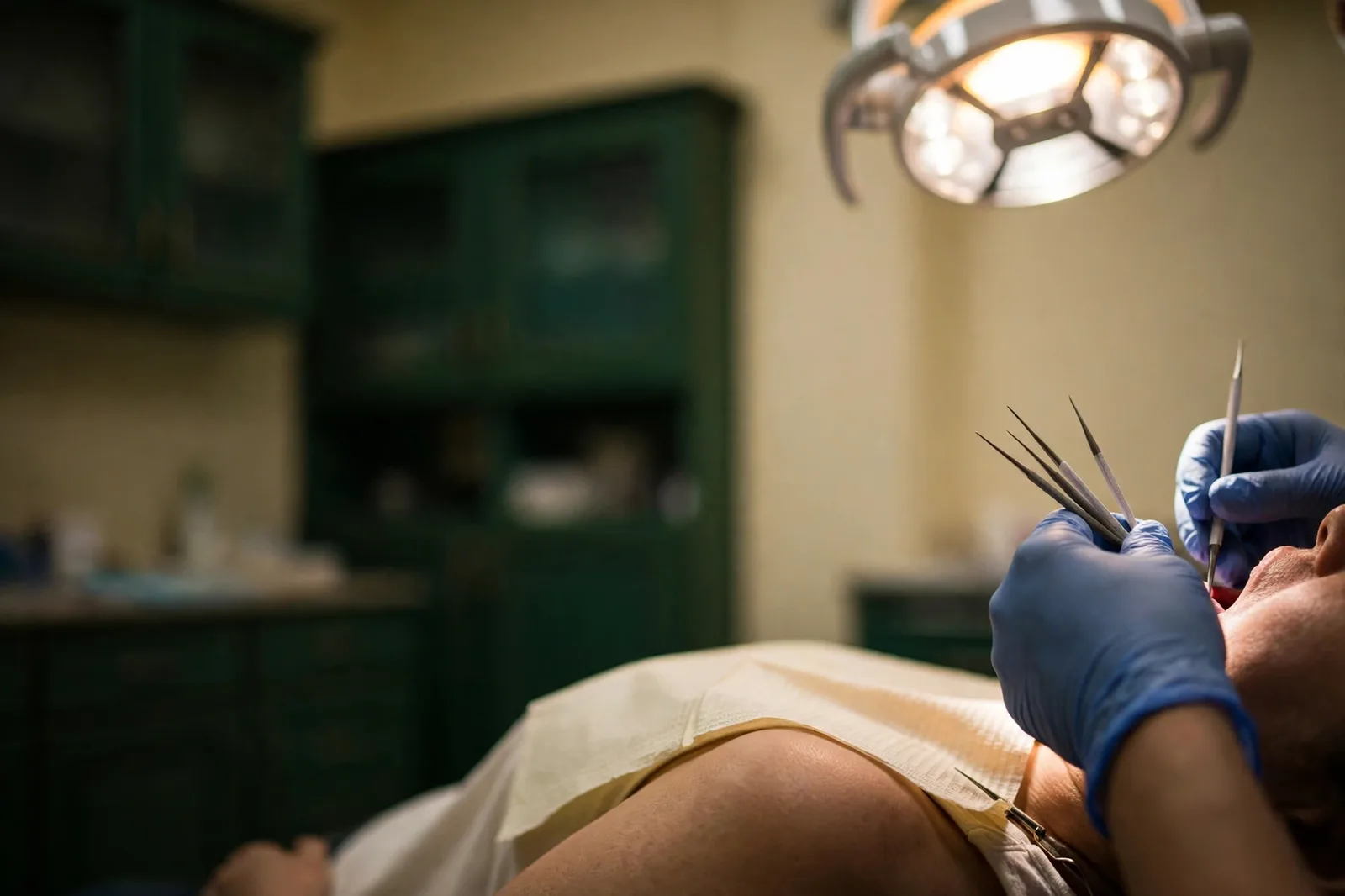 A dentist's gloved hands at work under the operating light